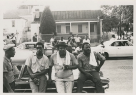 group of four Black men standing next to a car
